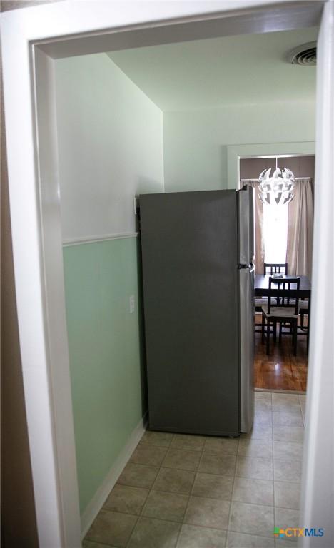 kitchen with visible vents, an inviting chandelier, light tile patterned flooring, and freestanding refrigerator