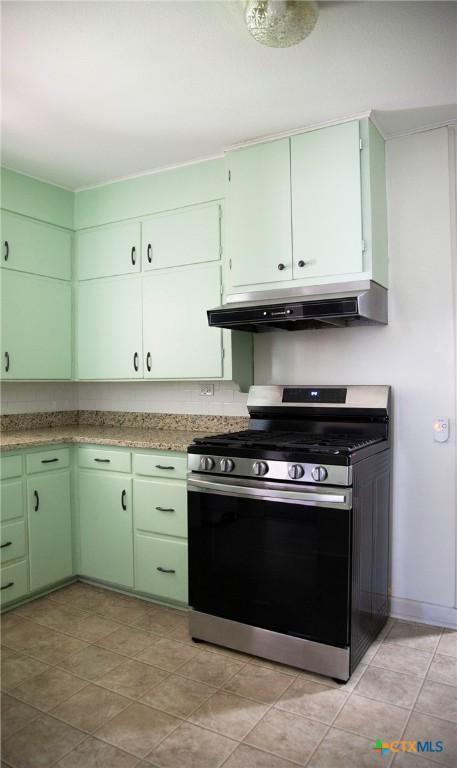 kitchen with under cabinet range hood, gas range, green cabinetry, and light countertops