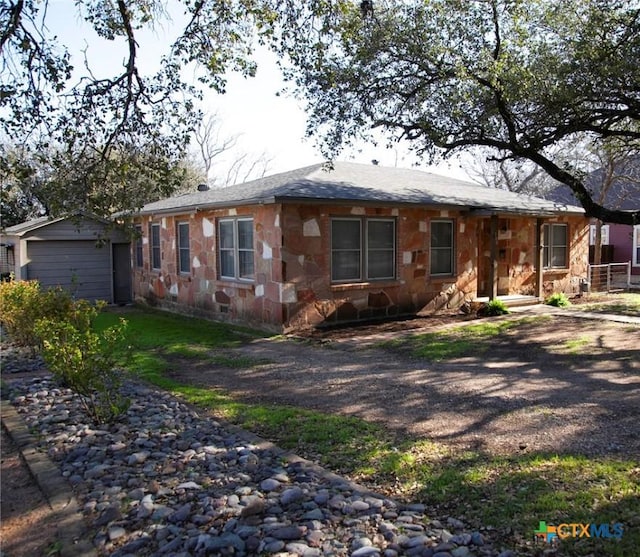 ranch-style home with stone siding and an outbuilding