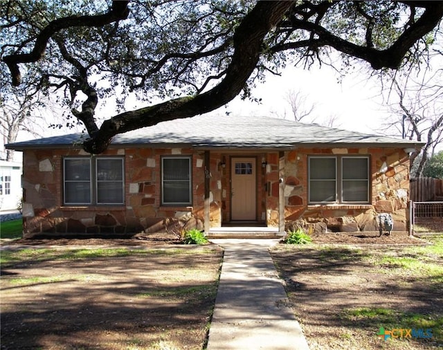 view of front of house with stone siding and fence