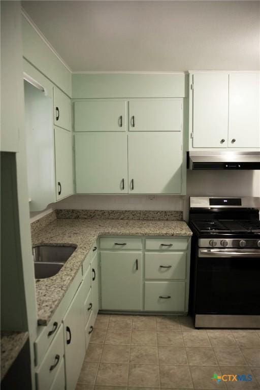 kitchen featuring stainless steel range with gas cooktop, under cabinet range hood, light tile patterned floors, white cabinetry, and a sink