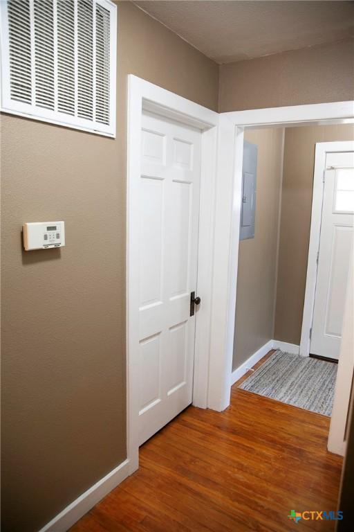 hall with visible vents, baseboards, and wood finished floors