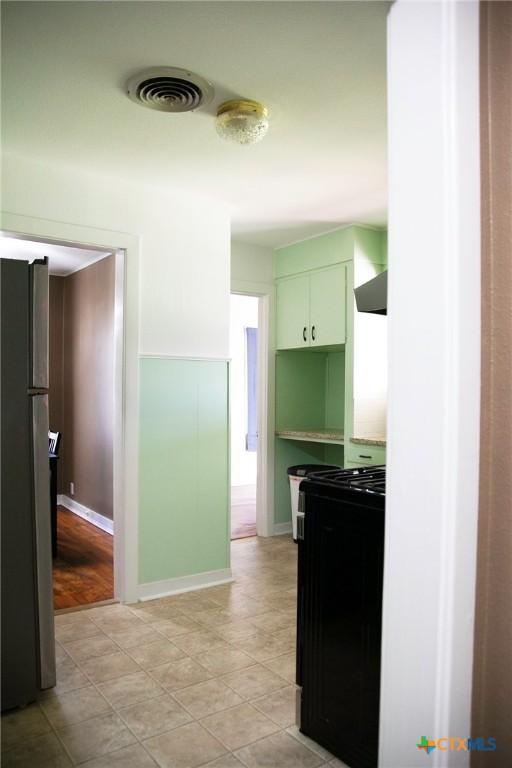 kitchen featuring visible vents, black appliances, and wall chimney exhaust hood