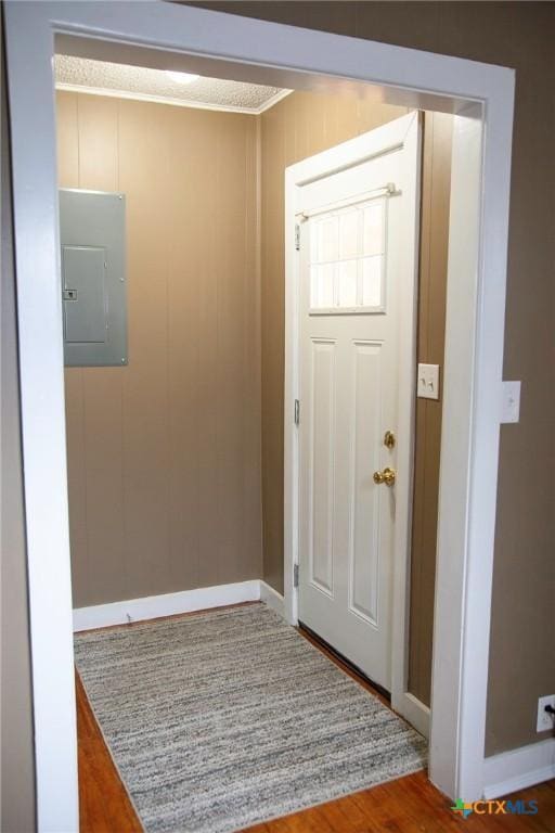 entryway with electric panel, wood finished floors, and baseboards