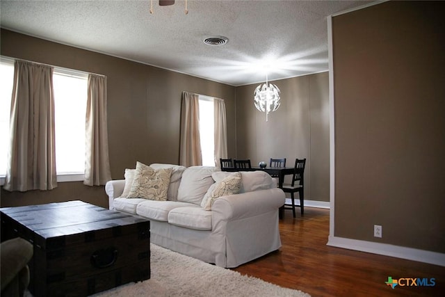 living room with a notable chandelier, wood finished floors, visible vents, and a wealth of natural light