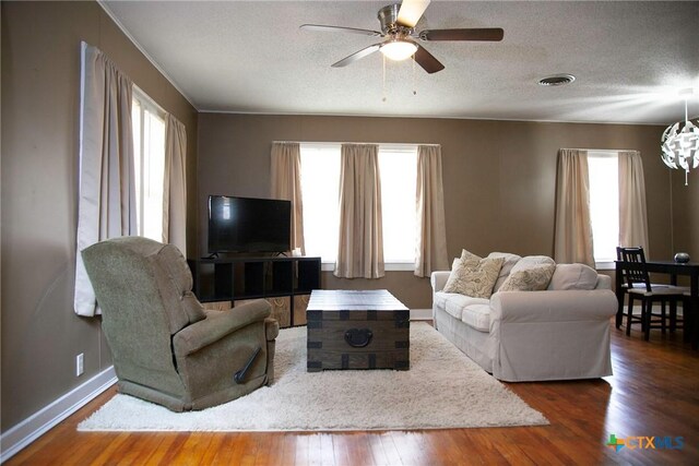 living area with visible vents, a textured ceiling, a healthy amount of sunlight, and wood finished floors