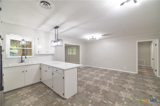 kitchen featuring white cabinets, hanging light fixtures, sink, and kitchen peninsula