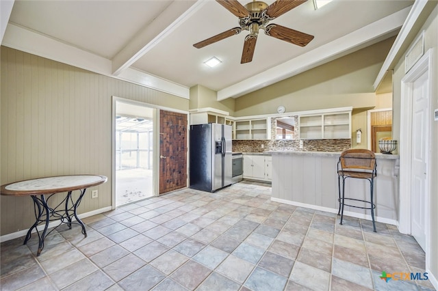 kitchen featuring a kitchen bar, a peninsula, stainless steel refrigerator with ice dispenser, white cabinets, and a ceiling fan