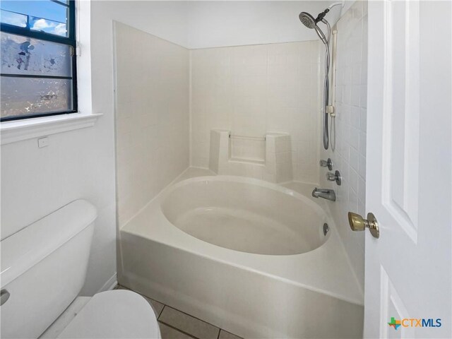 bathroom featuring washtub / shower combination, tile patterned floors, and toilet