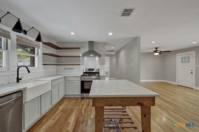 163 S Mesquite Ave, New Braunfels, TX 78130 - kitchen with stainless steel appliances, wall chimney exhaust hood, backsplash, open shelves, and light stone countertops