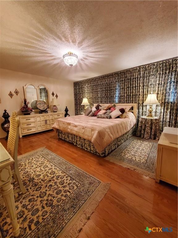 313 N Church, Goliad, TX 77963 - bedroom featuring wood finished floors and a textured ceiling