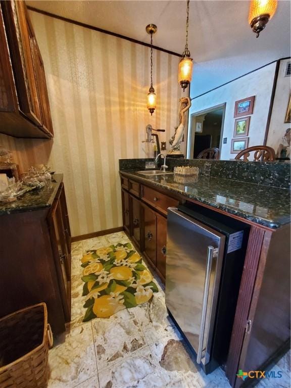 313 N Church, Goliad, TX 77963 - kitchen with wallpapered walls, a peninsula, pendant lighting, dark stone countertops, and baseboards