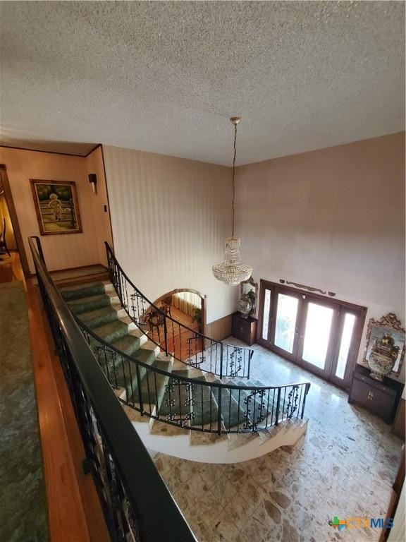 313 N Church, Goliad, TX 77963 - stairway featuring a chandelier, french doors, and a textured ceiling