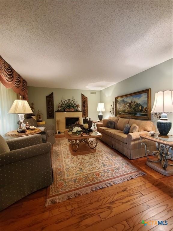 313 N Church, Goliad, TX 77963 - living room with hardwood / wood-style floors, a textured ceiling, and a fireplace