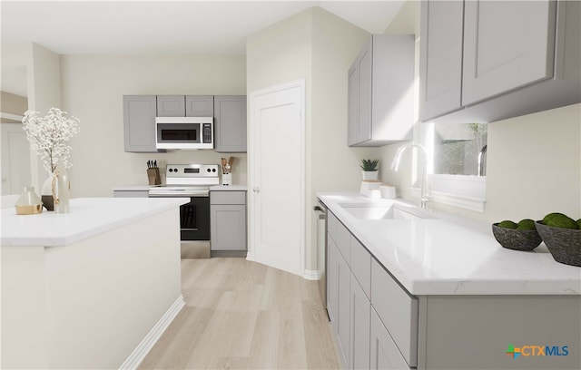 kitchen featuring gray cabinetry, sink, appliances with stainless steel finishes, and light hardwood / wood-style flooring