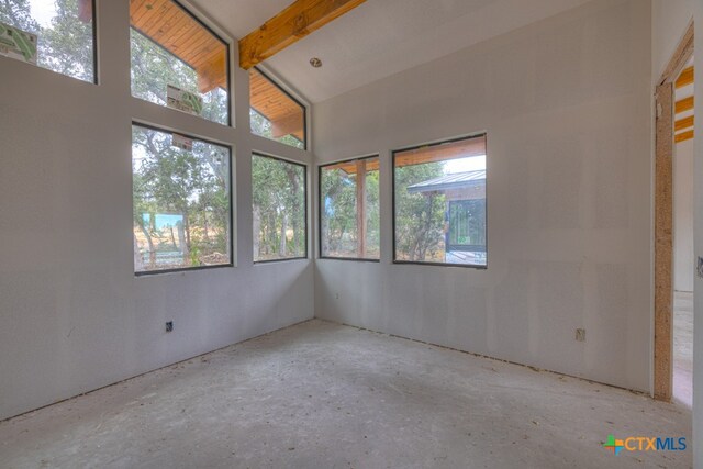 empty room featuring vaulted ceiling with beams