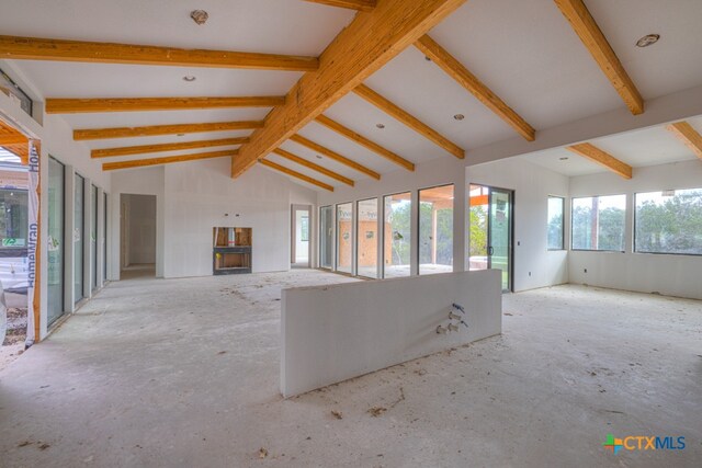 unfurnished living room with vaulted ceiling with beams and plenty of natural light