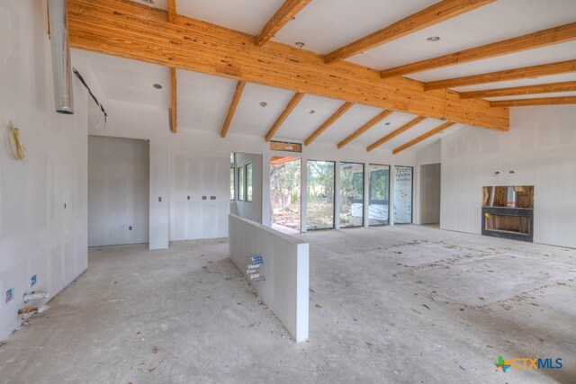 unfurnished living room with vaulted ceiling with beams