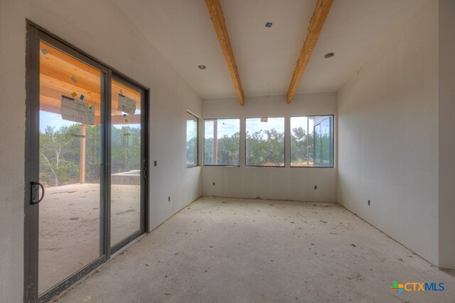 unfurnished sunroom featuring beamed ceiling and plenty of natural light