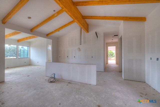 empty room with lofted ceiling with beams and a wealth of natural light