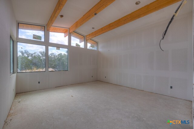 empty room featuring vaulted ceiling with beams