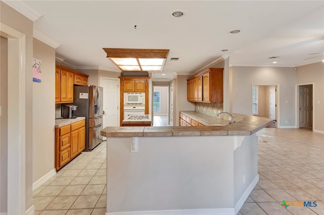 kitchen with plenty of natural light, kitchen peninsula, tile counters, and white appliances