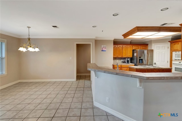 kitchen featuring backsplash, crown molding, white appliances, a kitchen bar, and light tile patterned floors