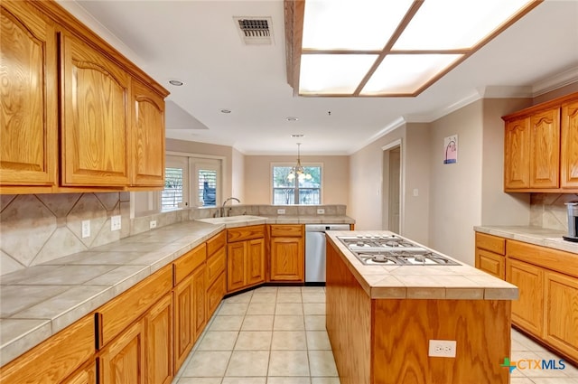 kitchen featuring appliances with stainless steel finishes, tasteful backsplash, sink, tile countertops, and a center island