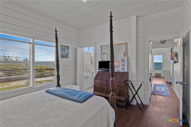 bedroom with crown molding, wood walls, and hardwood / wood-style flooring