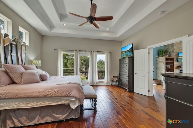 bedroom featuring dark hardwood / wood-style flooring, a tray ceiling, and ceiling fan