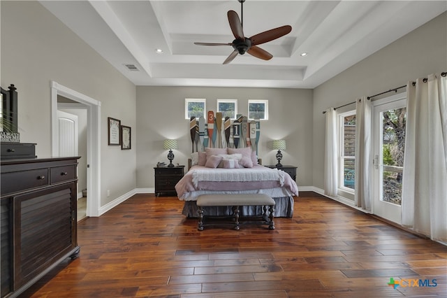 bedroom with dark wood-type flooring, a tray ceiling, ceiling fan, and access to exterior