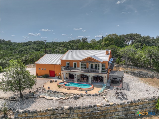 back of house featuring a patio, a swimming pool with hot tub, and a balcony