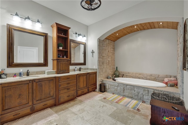 bathroom featuring tiled bath and vanity