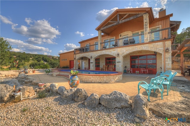 back of property featuring a jacuzzi, a balcony, and a patio area