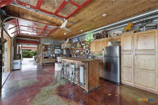 kitchen featuring butcher block counters, stainless steel refrigerator, light brown cabinetry, wood ceiling, and a kitchen island