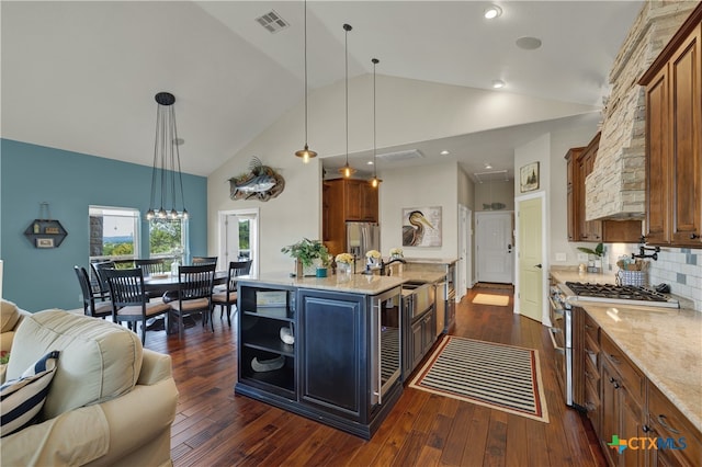 kitchen featuring stainless steel appliances, dark wood-type flooring, an island with sink, high vaulted ceiling, and pendant lighting