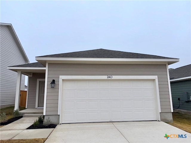 single story home featuring concrete driveway, a garage, and a shingled roof