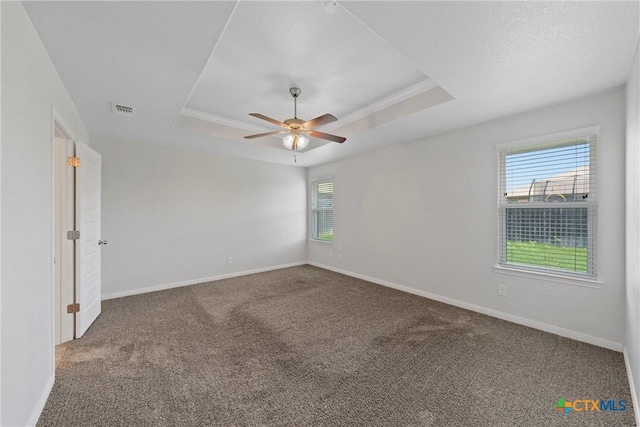 carpeted empty room featuring a tray ceiling, a ceiling fan, and baseboards