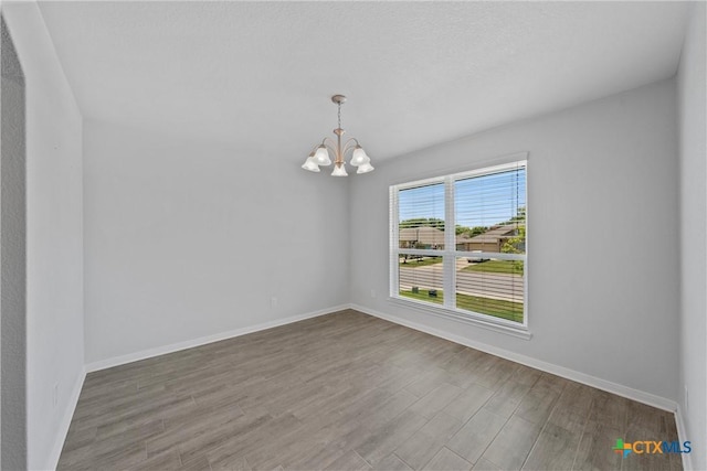unfurnished dining area with a chandelier, baseboards, and wood finished floors