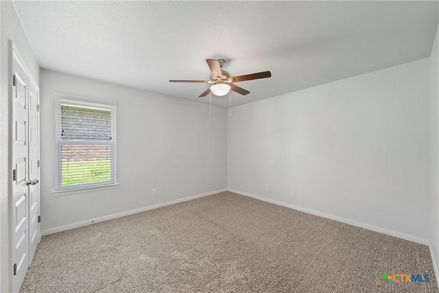 carpeted empty room featuring ceiling fan and baseboards