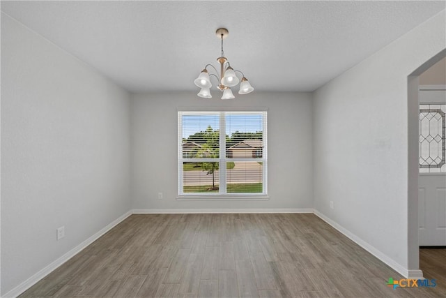 unfurnished dining area featuring a chandelier, wood finished floors, and baseboards