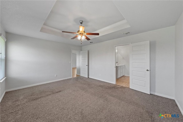 unfurnished bedroom featuring a raised ceiling, light colored carpet, baseboards, and ornamental molding