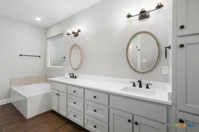 bathroom with wood-type flooring, a bathtub, and vanity