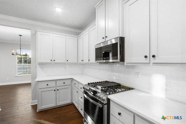 kitchen featuring appliances with stainless steel finishes, white cabinetry, dark wood-type flooring, and ornamental molding