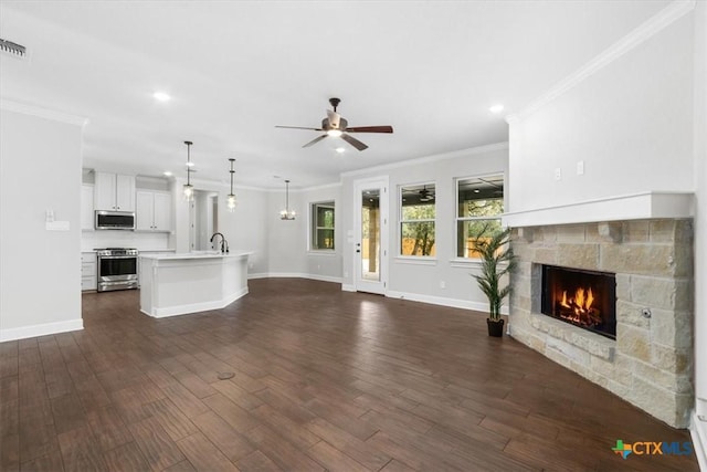 unfurnished living room featuring crown molding, dark hardwood / wood-style flooring, a fireplace, and sink