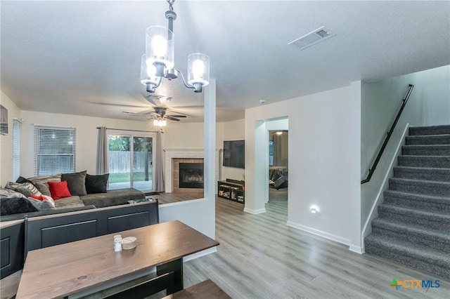 5304 Oster Dr, Killeen, TX 76542 - living room with a ceiling fan, light wood-style floors, stairs, a tiled fireplace, and a chandelier