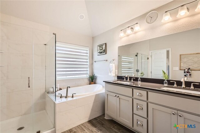3256 Pablo Cir, Round Rock, TX 78665 - full bathroom featuring double vanity, a bath, a shower stall, wood finish floors, and vaulted ceiling