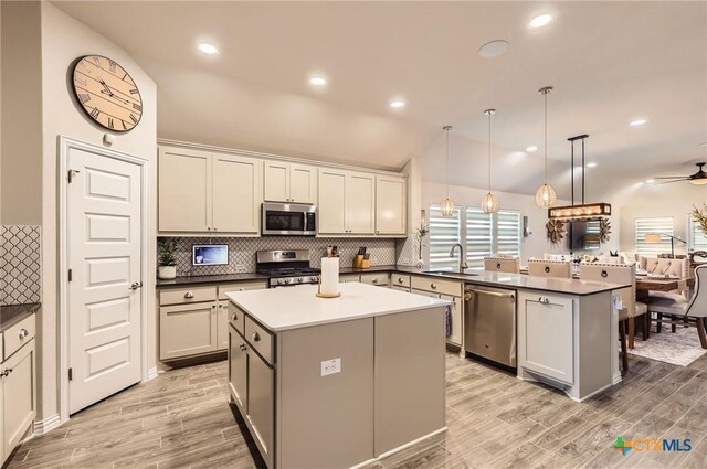 3256 Pablo Cir, Round Rock, TX 78665 - kitchen featuring appliances with stainless steel finishes, a peninsula, light wood-style floors, backsplash, and lofted ceiling