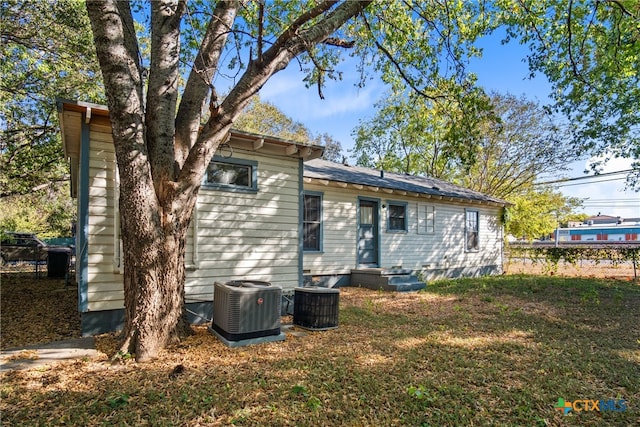 rear view of house featuring a lawn and central air condition unit