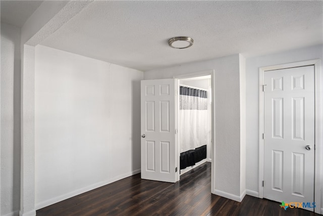 bedroom with a textured ceiling and dark wood-type flooring